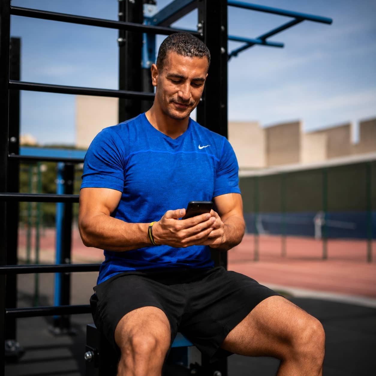 Coach Fathi reviewing a training plan on his phone while supervising a client during an outdoor fitness session, demonstrating personalized coaching, guidance, and support throughout the rehabilitation journey.